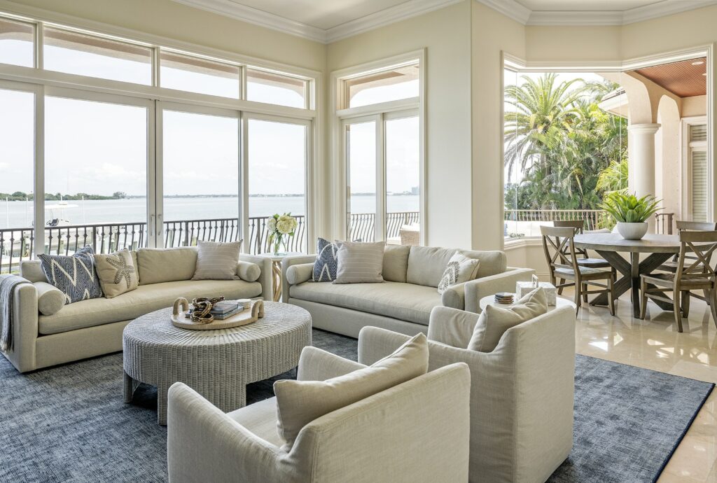 Waterfront living and dining room spaces with views of the water and beautiful palm trees